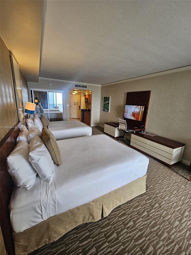 carpeted bedroom with a textured ceiling and ornamental molding