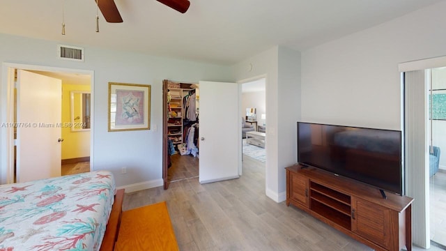 bedroom with a walk in closet, light hardwood / wood-style floors, a closet, and ceiling fan