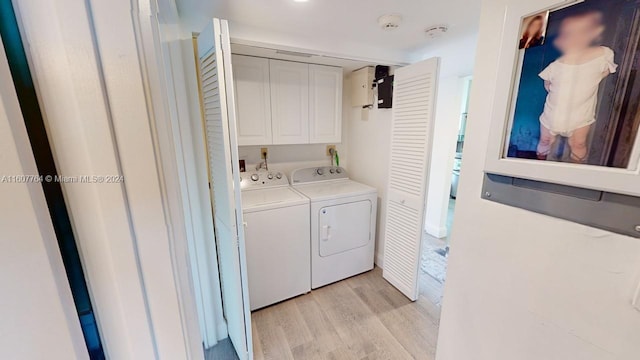 laundry room with cabinets, washing machine and dryer, and light wood-type flooring