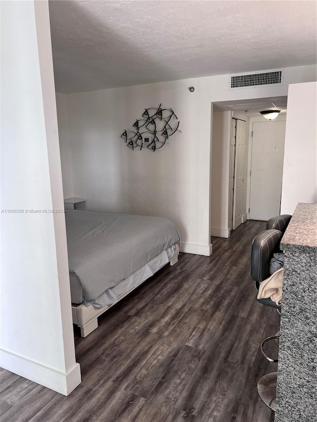 bedroom with dark hardwood / wood-style flooring and a textured ceiling