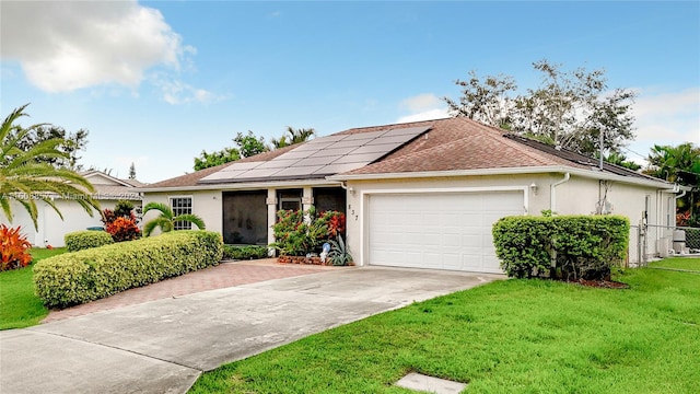 ranch-style house with a front yard, a garage, and solar panels