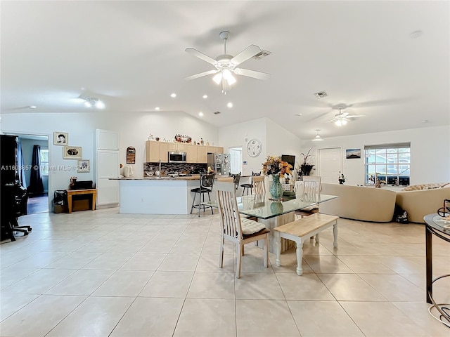 dining space with ceiling fan, light tile floors, and lofted ceiling