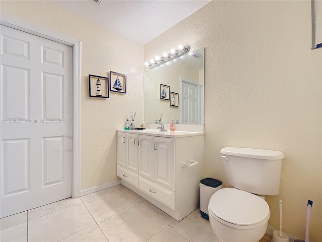 bathroom featuring tile flooring, vanity, toilet, and a textured ceiling