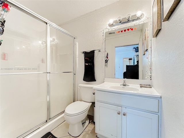 bathroom with tile floors, walk in shower, vanity with extensive cabinet space, and toilet