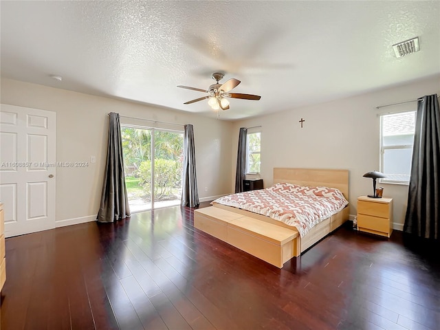 bedroom featuring dark hardwood / wood-style flooring, ceiling fan, a textured ceiling, and access to outside