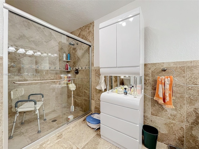 bathroom with tile walls, walk in shower, tile flooring, and a textured ceiling