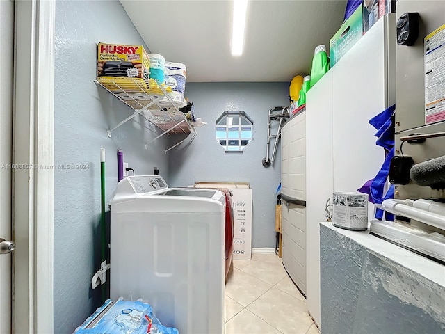 laundry area with independent washer and dryer and light tile floors