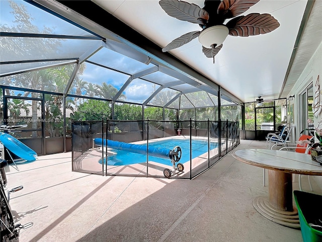 view of swimming pool featuring a patio, glass enclosure, and ceiling fan