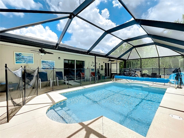 view of swimming pool featuring a patio, glass enclosure, ceiling fan, and a water slide