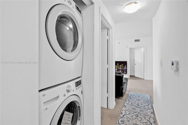 laundry room featuring light carpet and stacked washer and clothes dryer