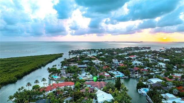 aerial view at dusk featuring a water view