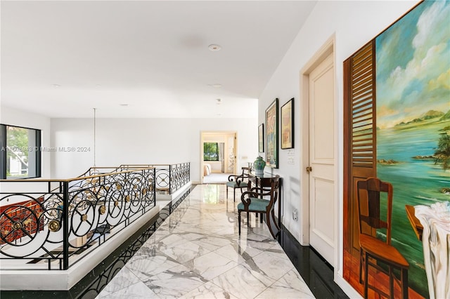 hall with a healthy amount of sunlight and light tile patterned floors