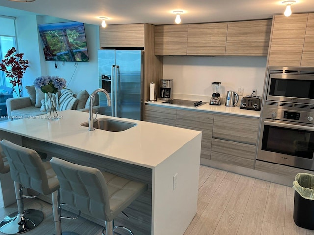 kitchen featuring a center island with sink, sink, a breakfast bar area, light hardwood / wood-style flooring, and stainless steel appliances