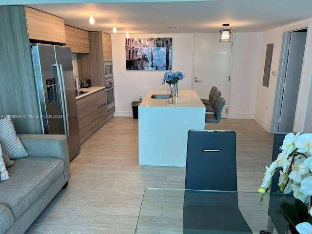 kitchen with appliances with stainless steel finishes, sink, light hardwood / wood-style flooring, a center island, and electric panel