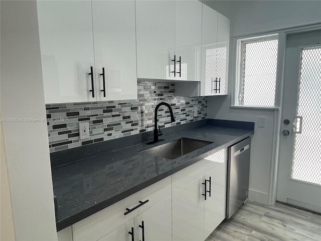 kitchen with dark stone counters, light hardwood / wood-style flooring, dishwasher, white cabinetry, and sink