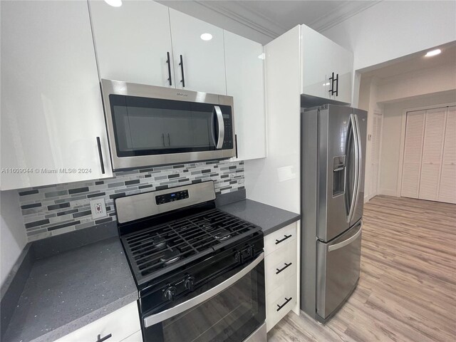 kitchen featuring light hardwood / wood-style flooring, tasteful backsplash, ornamental molding, white cabinets, and appliances with stainless steel finishes