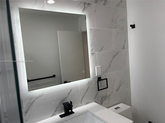 bathroom with tile walls, large vanity, and toilet