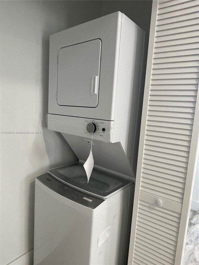 clothes washing area featuring stacked washer / drying machine and hardwood / wood-style floors