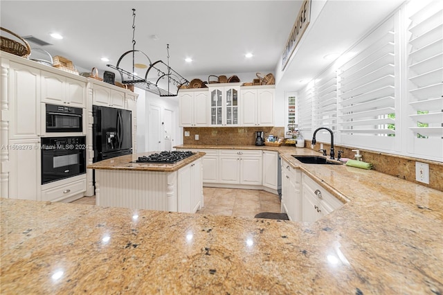 kitchen featuring backsplash, sink, black appliances, white cabinets, and a kitchen island