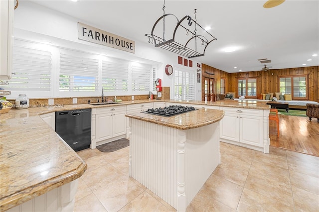 kitchen with light stone countertops, black dishwasher, a kitchen island, and sink