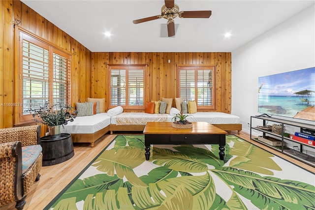 living room with wooden walls, ceiling fan, and hardwood / wood-style flooring