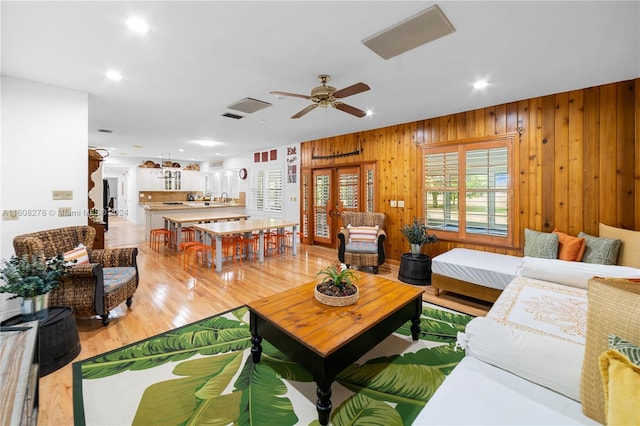 living room with wood walls, sink, ceiling fan, and hardwood / wood-style flooring