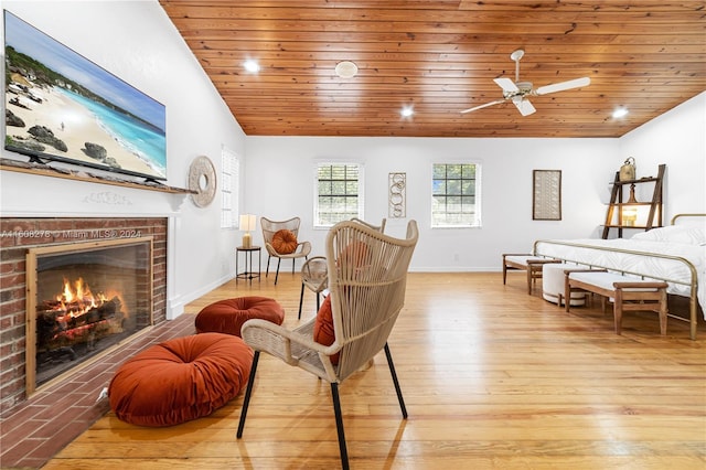 interior space with ceiling fan, light hardwood / wood-style floors, vaulted ceiling, a fireplace, and wood ceiling