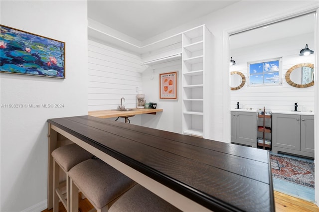 bar featuring gray cabinets, light hardwood / wood-style floors, and sink