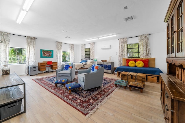 living room featuring a wall mounted AC and light hardwood / wood-style floors