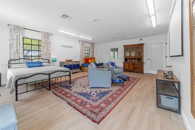 living room featuring a wall mounted air conditioner and light hardwood / wood-style floors