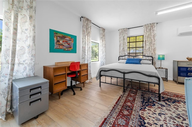 bedroom with light hardwood / wood-style floors and a wall mounted AC