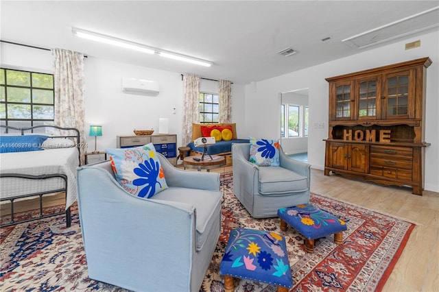 living room featuring a wall mounted AC and light hardwood / wood-style floors