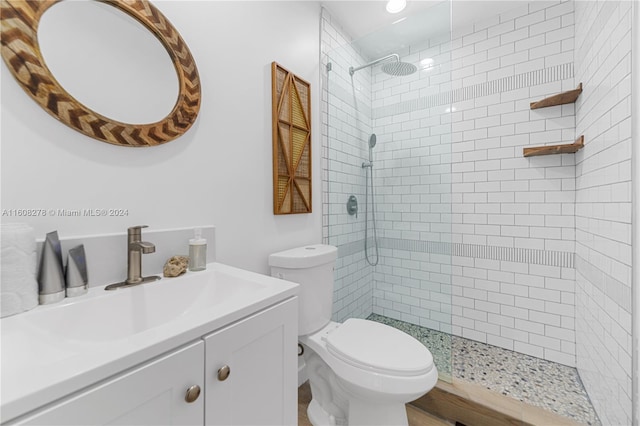 bathroom featuring a tile shower, vanity, and toilet