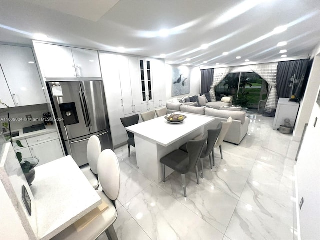 kitchen featuring white cabinetry and stainless steel refrigerator with ice dispenser