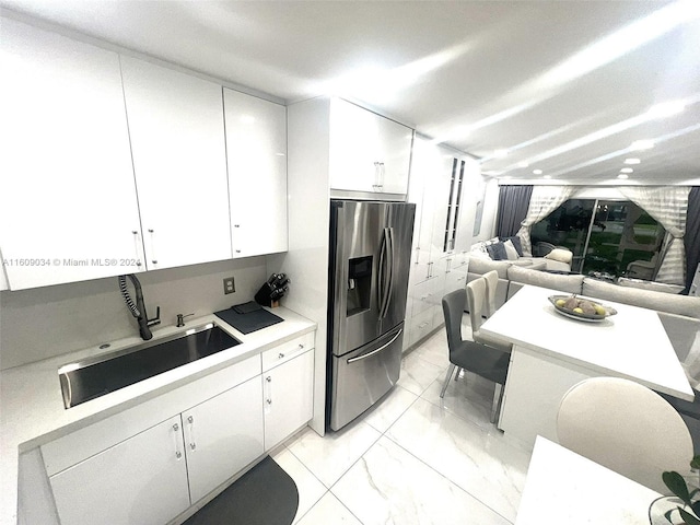 kitchen with stainless steel fridge, sink, and white cabinets