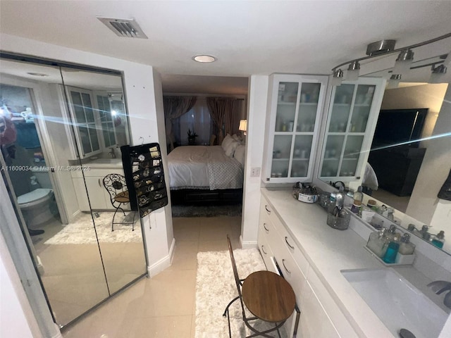 bedroom featuring light tile patterned floors, a closet, and sink