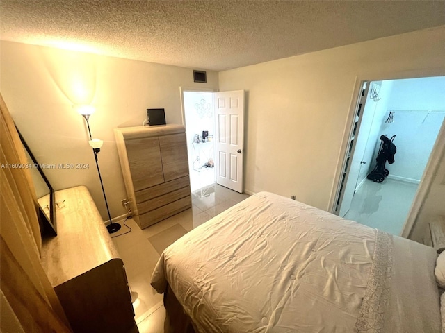 bedroom with a textured ceiling and light tile patterned flooring