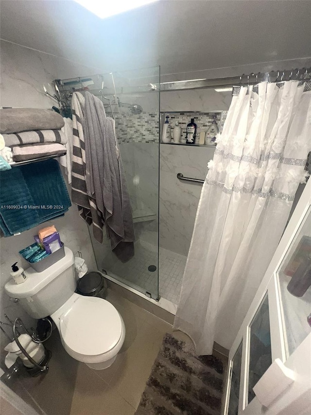 bathroom featuring tile patterned floors, toilet, and curtained shower