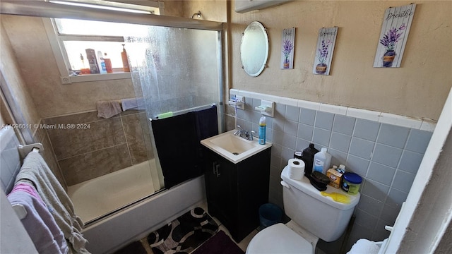 bathroom with vanity, tile walls, toilet, and an enclosed shower