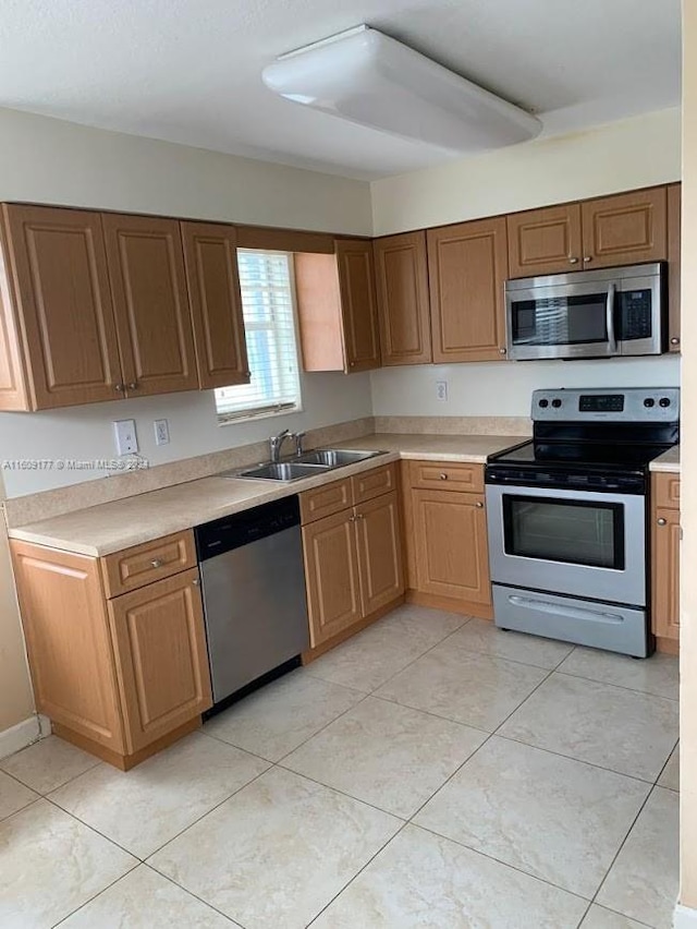 kitchen featuring stainless steel appliances, sink, and light tile floors