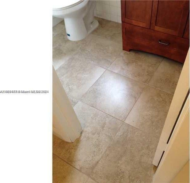 bathroom with tile flooring, toilet, and vanity