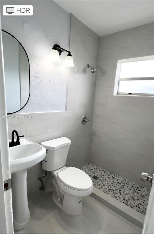 bathroom featuring tile walls, toilet, and tiled shower