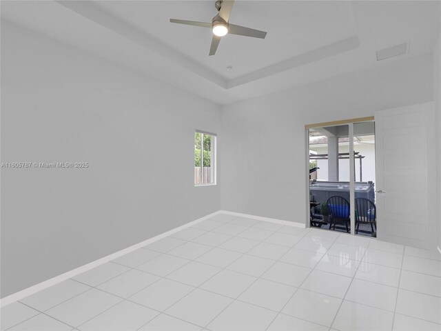 spare room featuring a raised ceiling, light tile patterned floors, and ceiling fan