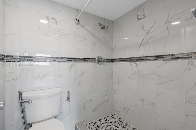 bathroom featuring a tile shower and toilet