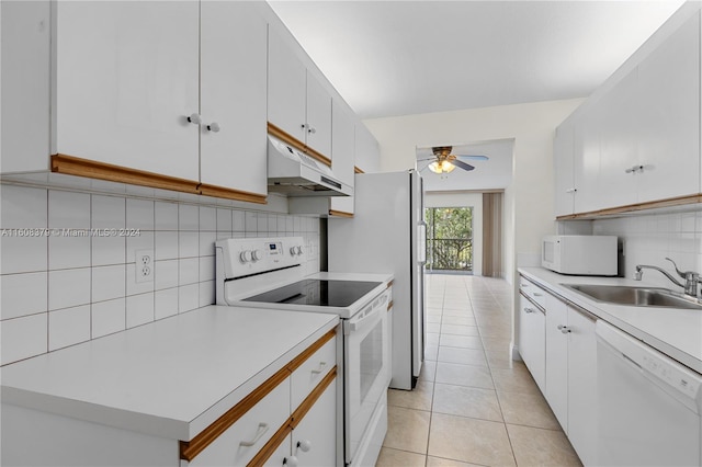 kitchen featuring white appliances, light tile patterned flooring, sink, white cabinetry, and decorative backsplash