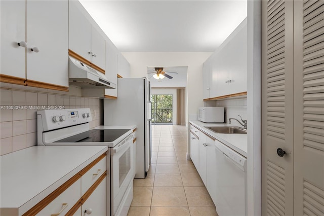 kitchen with white appliances, sink, white cabinetry, decorative backsplash, and light tile patterned floors