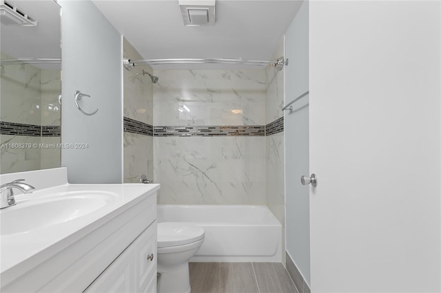 full bathroom featuring vanity, tiled shower / bath combo, hardwood / wood-style flooring, and toilet