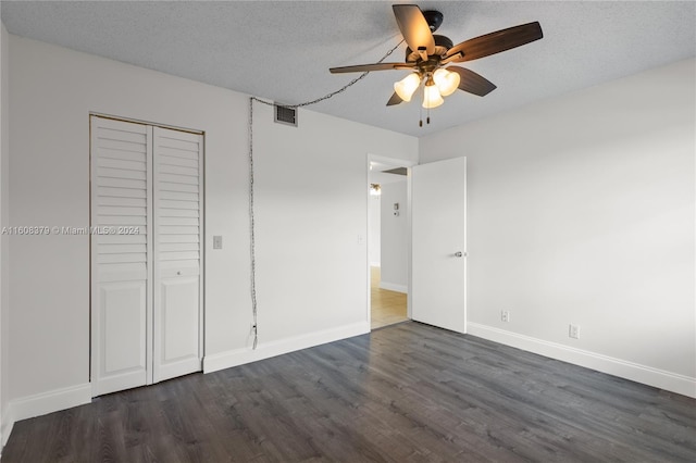 unfurnished bedroom featuring dark hardwood / wood-style flooring, a closet, a textured ceiling, and ceiling fan