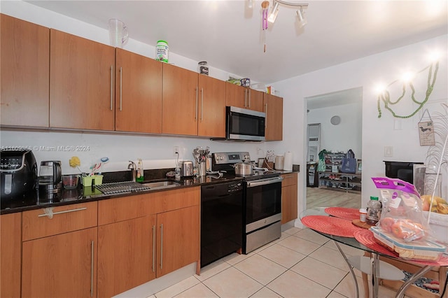 kitchen featuring sink, appliances with stainless steel finishes, dark stone countertops, and light tile patterned floors