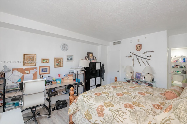 bedroom with light hardwood / wood-style floors and a textured ceiling